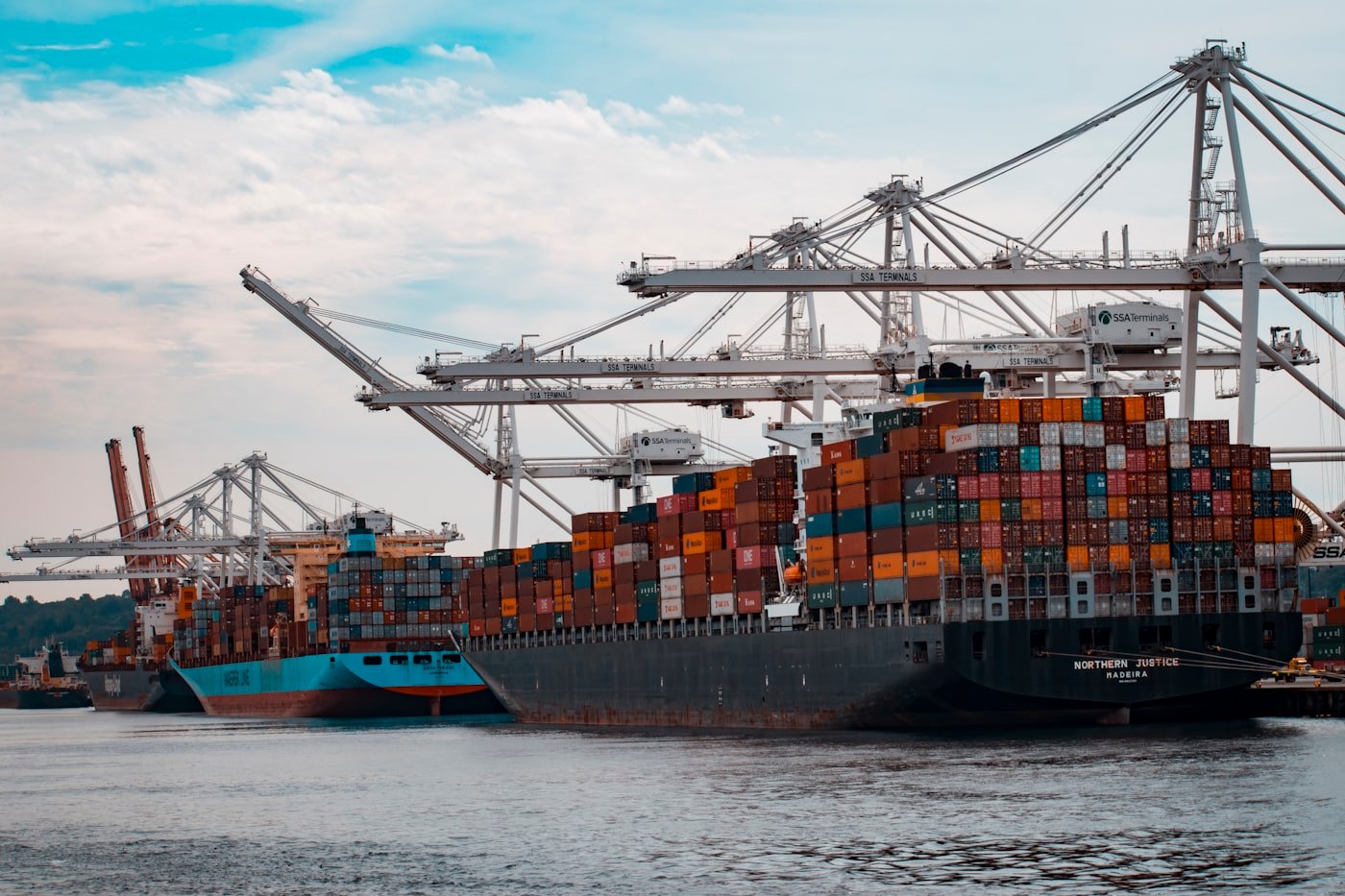 Large container ship being loaded by cranes at a busy port